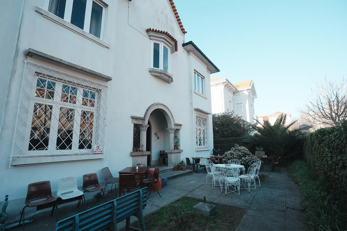Fachada branca da casa da Escola Normal no Porto, com arco de pedra e jardim